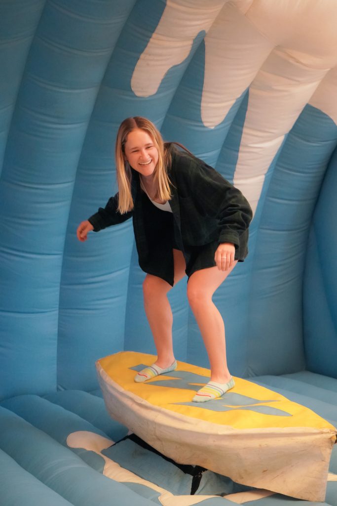 A student surfing on the inflatable surf simulator.