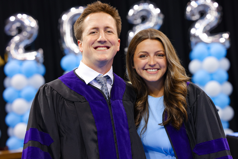 Two students pose with each other by their seats in Carmichael Arena before commencement.