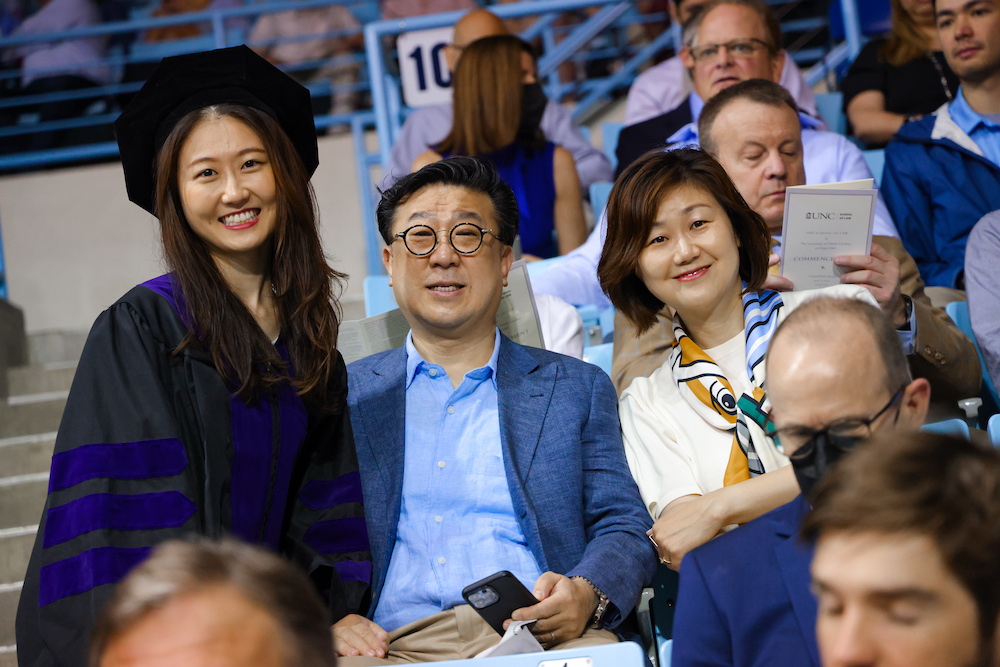 A student poses with their family in the stands before commencement.