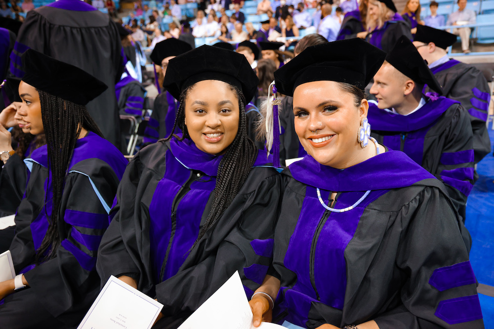 Adreanna Sellers and Gabrielle James pose with each other in their seats in Carmichael Arena before commencement.
