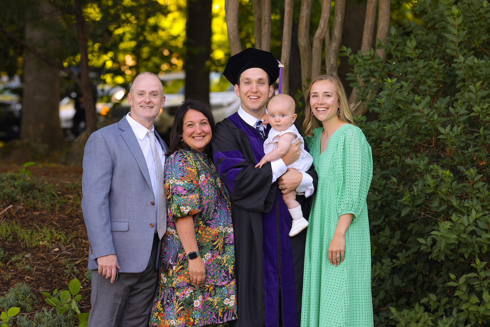 A family poses with their graduate in the gardens outside of the law school before commencement.