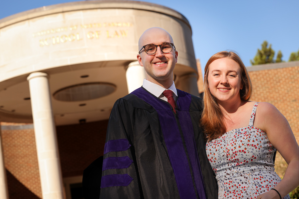 A student poses with their girlfriend outside of the law school after commencement.