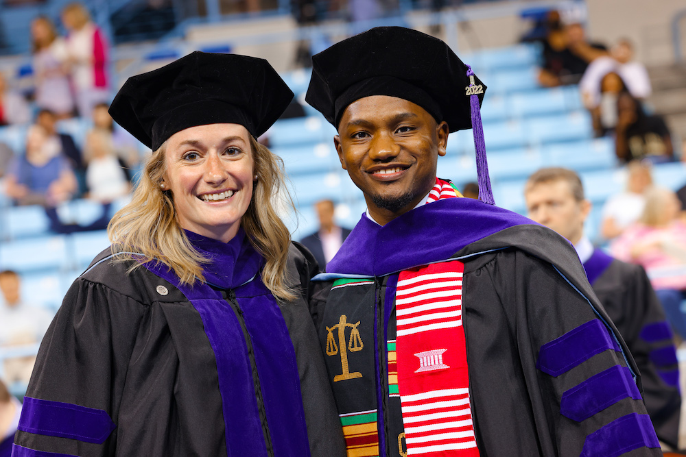 Julie Leopold and Trey Ellis pose with each other by their seats in Carmichael Arena before commencement.